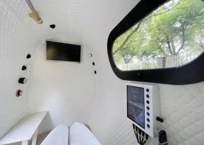 Inside view of oval walk-in hyperbaric chamber showing trees outside large viewing window
